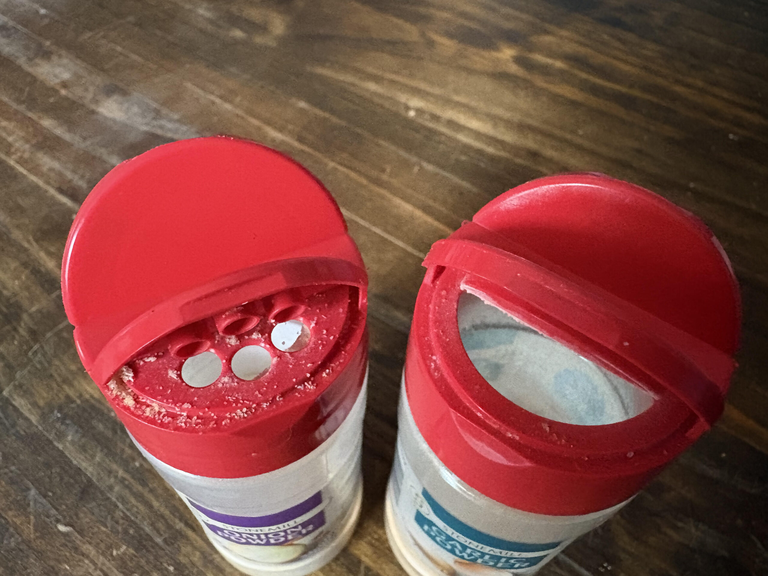 The tops of my spice containers, showing red tops with one side for spooning and one for shaking.
